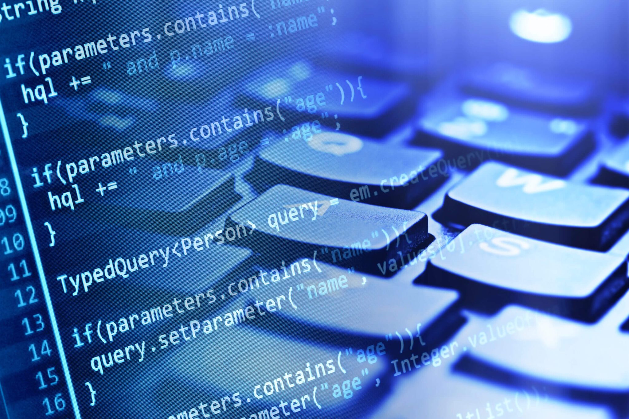 Close-up of a computer keyboard tinted in blue, with white programming language placed on top. This represents our use of the MuleSoft application for networking software systems.